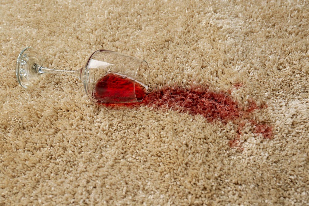 overturned glass and spilled red wine on soft carpet